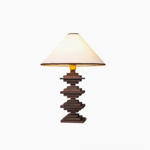 Walnut stacked wood tower table lamp with cream fabric shade and gold trim, studio white background