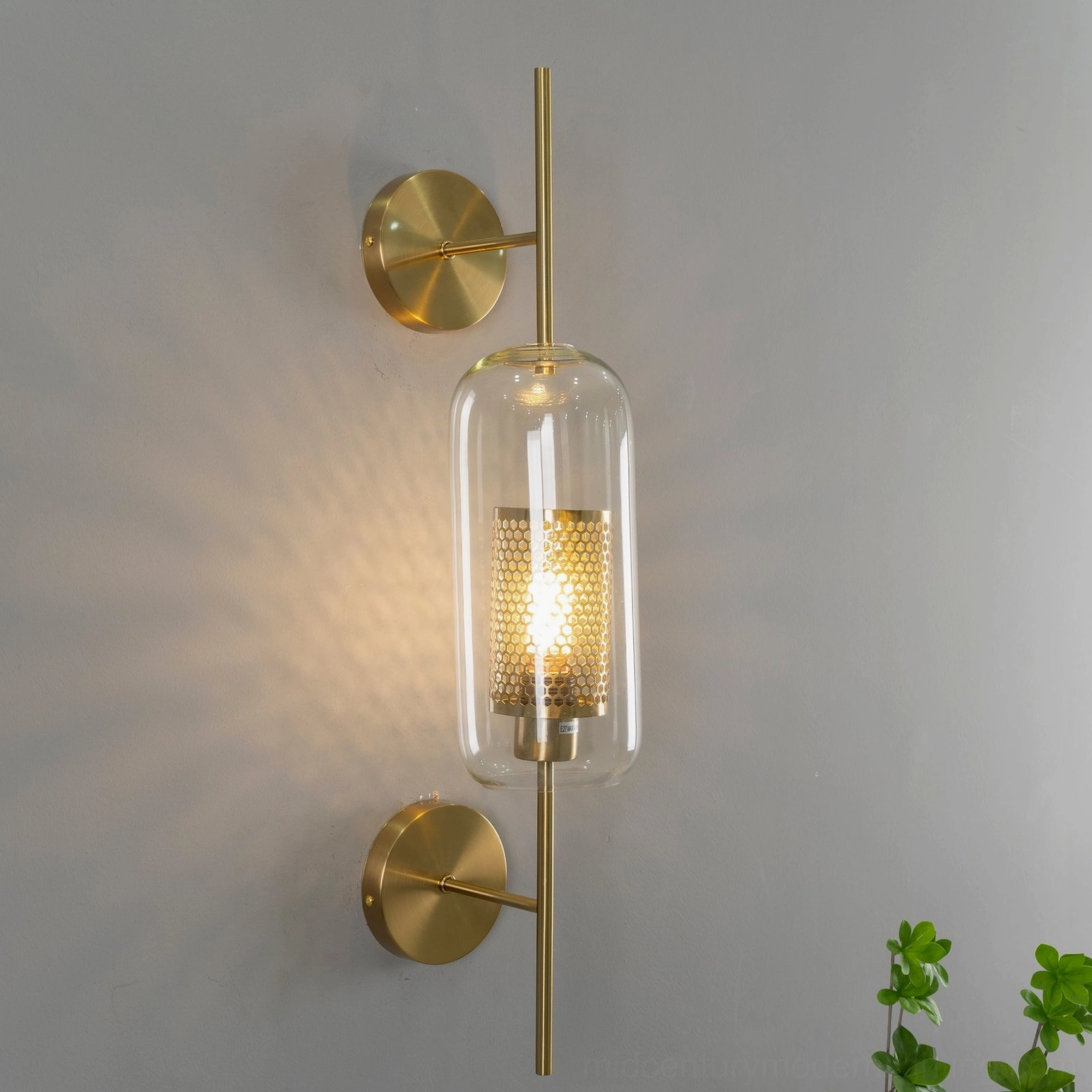 Contemporary glass wall sconce with warm brass finish and geometric proportions