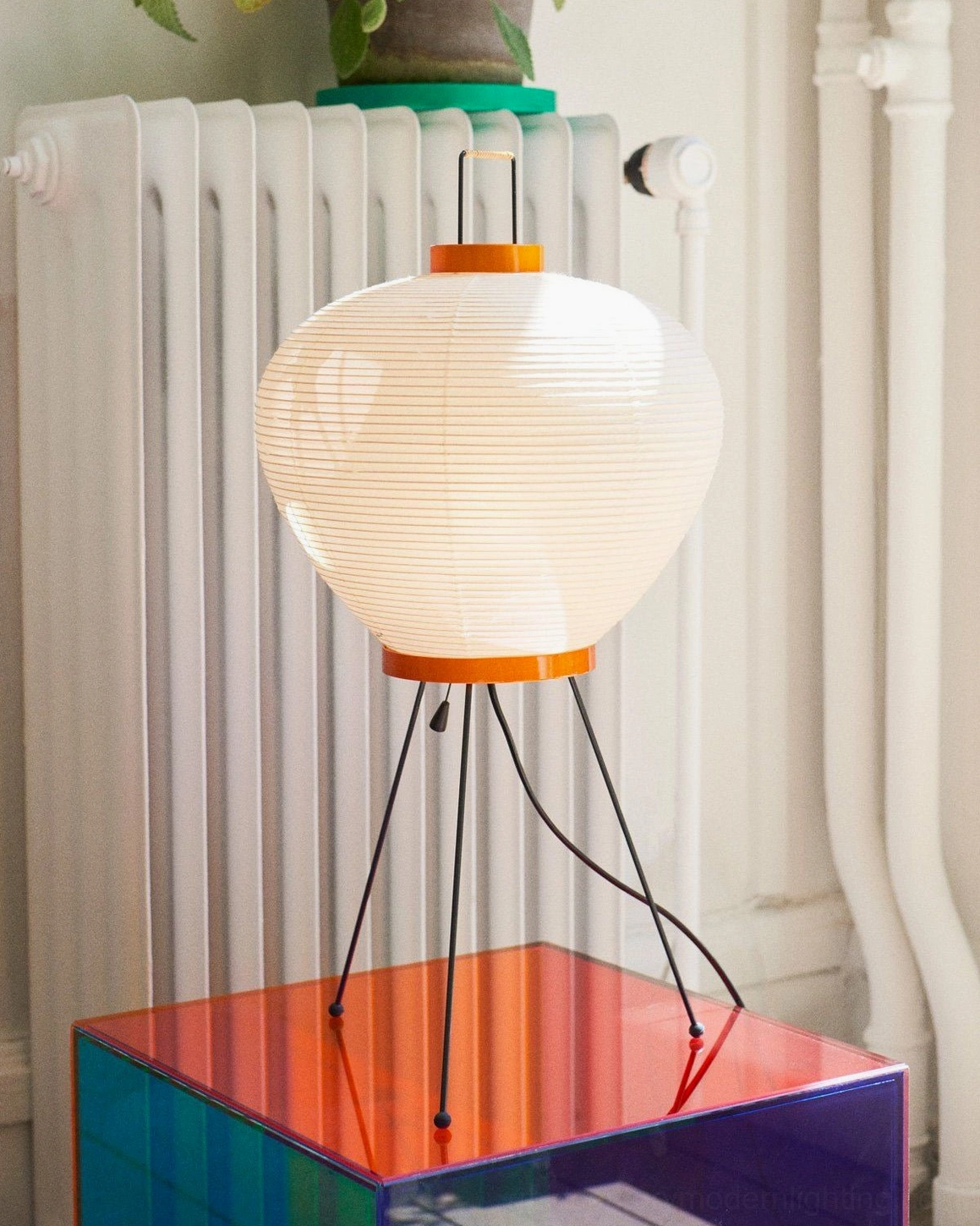 Washi mulberry paper table lamp beside iridescent side table in minimalist home corner with radiator
