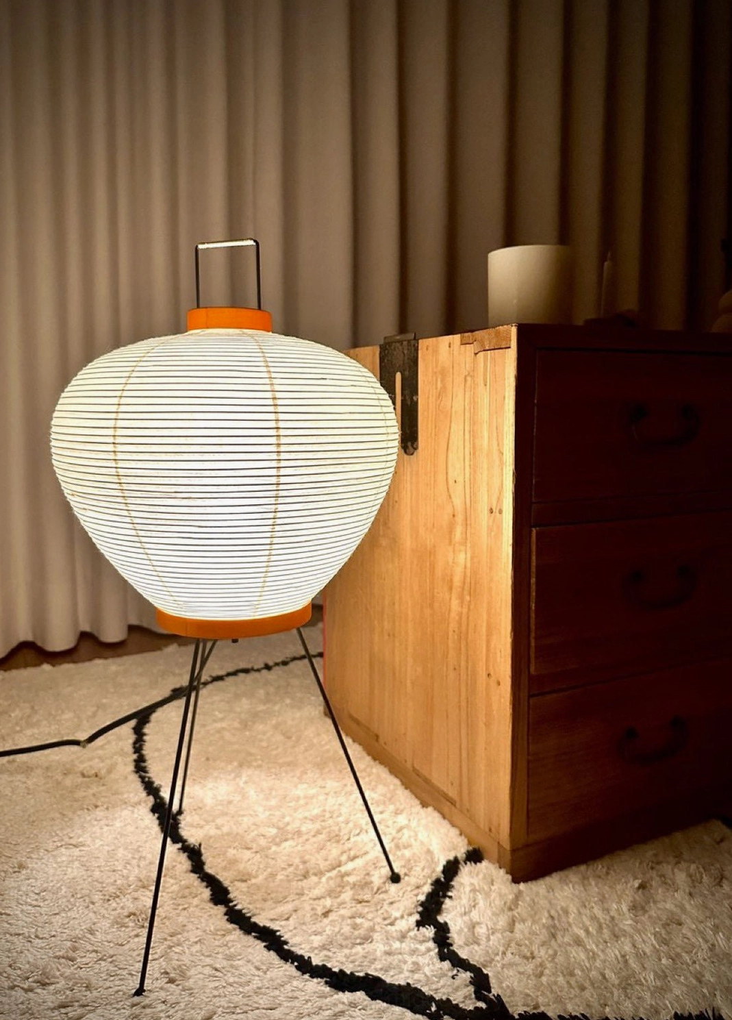 Washi Japanese table lamp in warm minimalist bedroom corner with wooden dresser and area rug