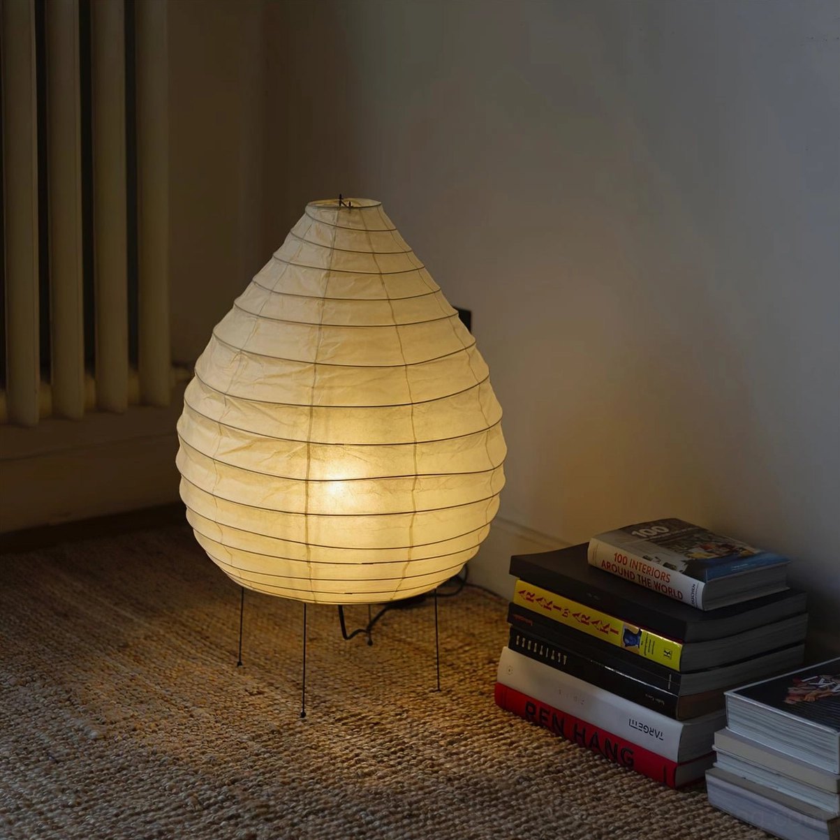 Handcrafted washi lamp in minimalist living room with stacked books, wabi-sabi interior styling