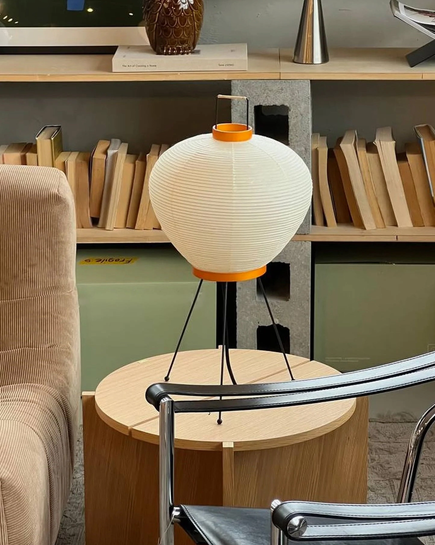 Washi tripod table lamp in mid-century modern home library with natural wood bookshelf and seating area