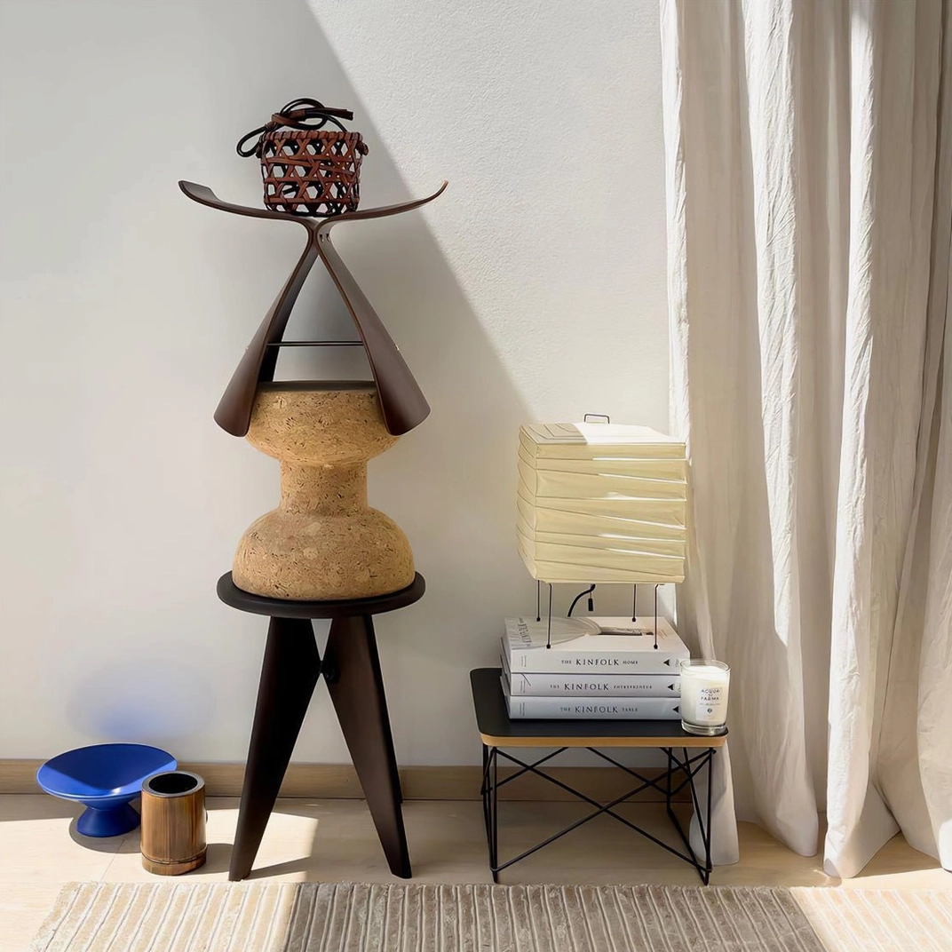 Contemporary sculptural paper table lamp on stacked books with Nordic decorative side table, corner placement in minimalist living space