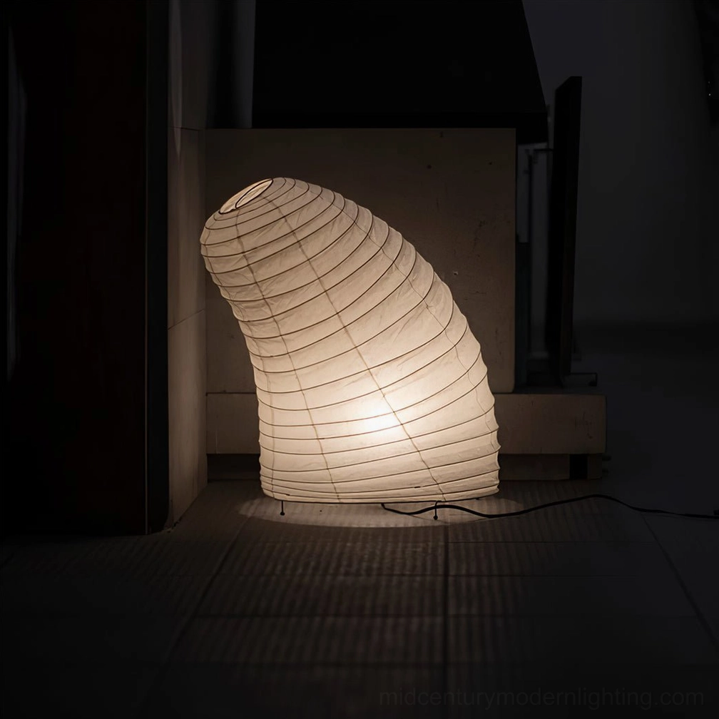 Japanese washi paper table lamp side three-quarter view in dark indoor corner with tiled flooring, demonstrating soft light diffusion