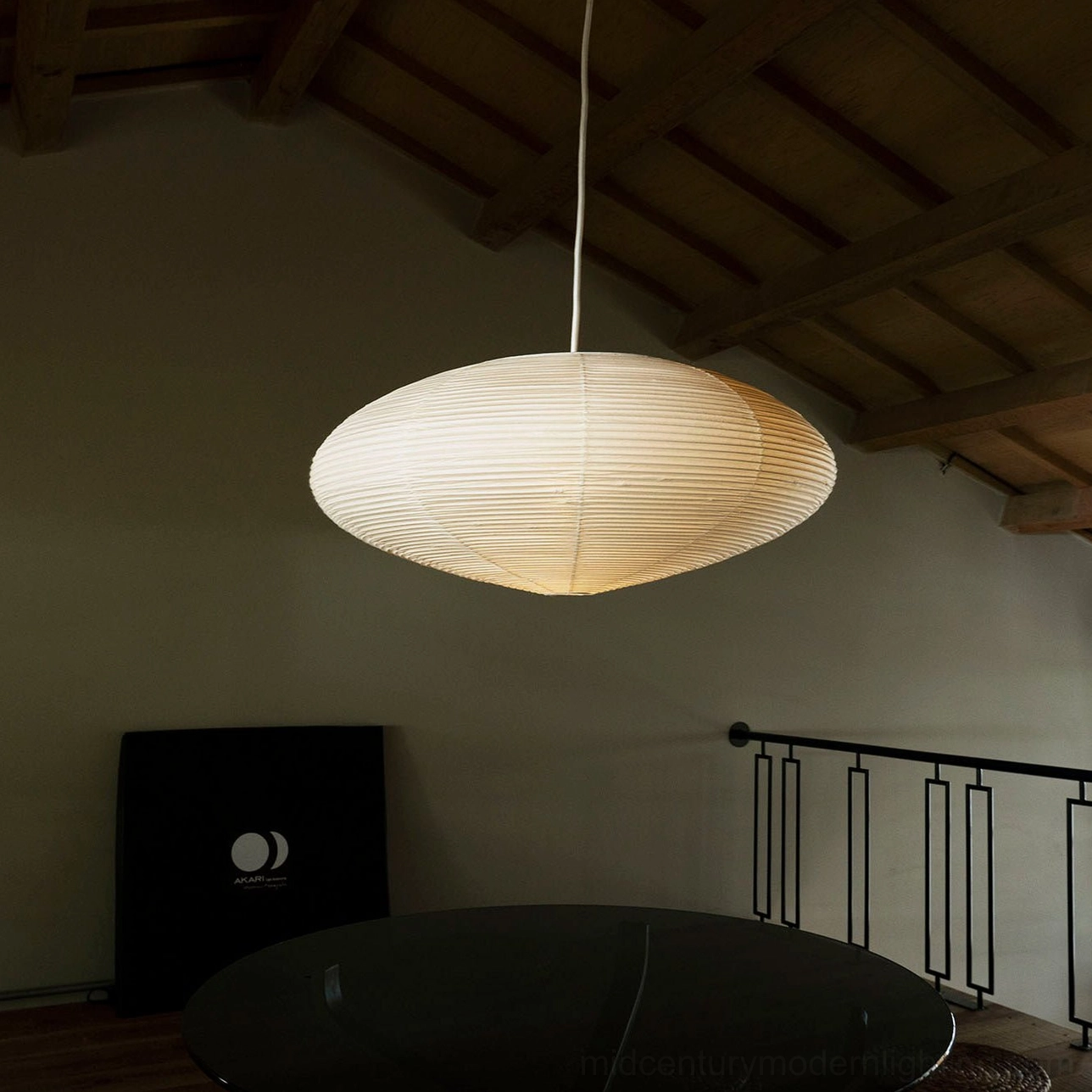Washi paper pendant installed in loft-style living space with exposed wooden ceiling beams and warm ambient lighting