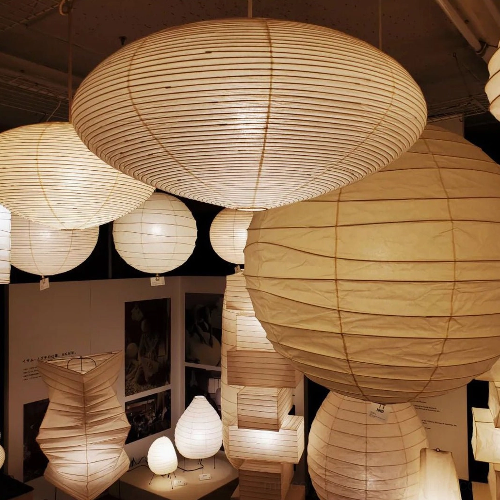 Multiple washi paper pendant light fixtures in various sizes displayed in contemporary lighting showroom