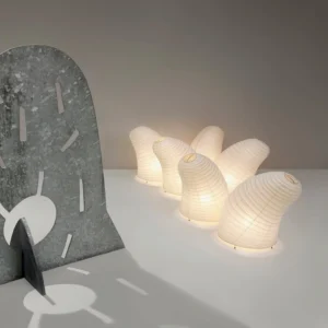 Collection of warm glowing washi paper table lamps displayed in minimalist interior setting, overhead flat lay perspective showing soft ambient lighting