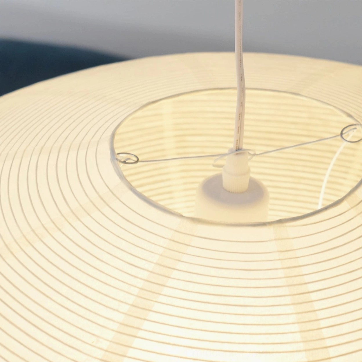 Washi paper pendant light turned on showing warm golden glow through translucent mulberry fiber shade