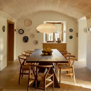 Washi paper pendant light suspended above vintage dining table in warm neutral interior with soft diffused glow