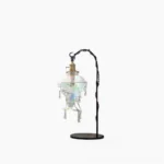 Water droplet resin table lamp side view with iridescent glass shade and metal base in studio setting