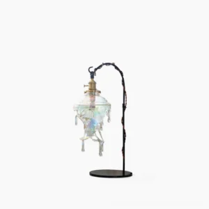 Water droplet resin table lamp side view with iridescent glass shade and metal base in studio setting