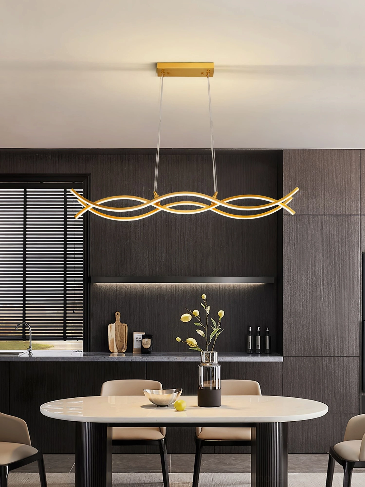 Brushed brass wave pendant chandelier illuminated in modern minimalist dining space