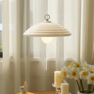 Wave glass pendant lamp hanging in dining room with sheer curtains and warm beige vintage cottage interior styling