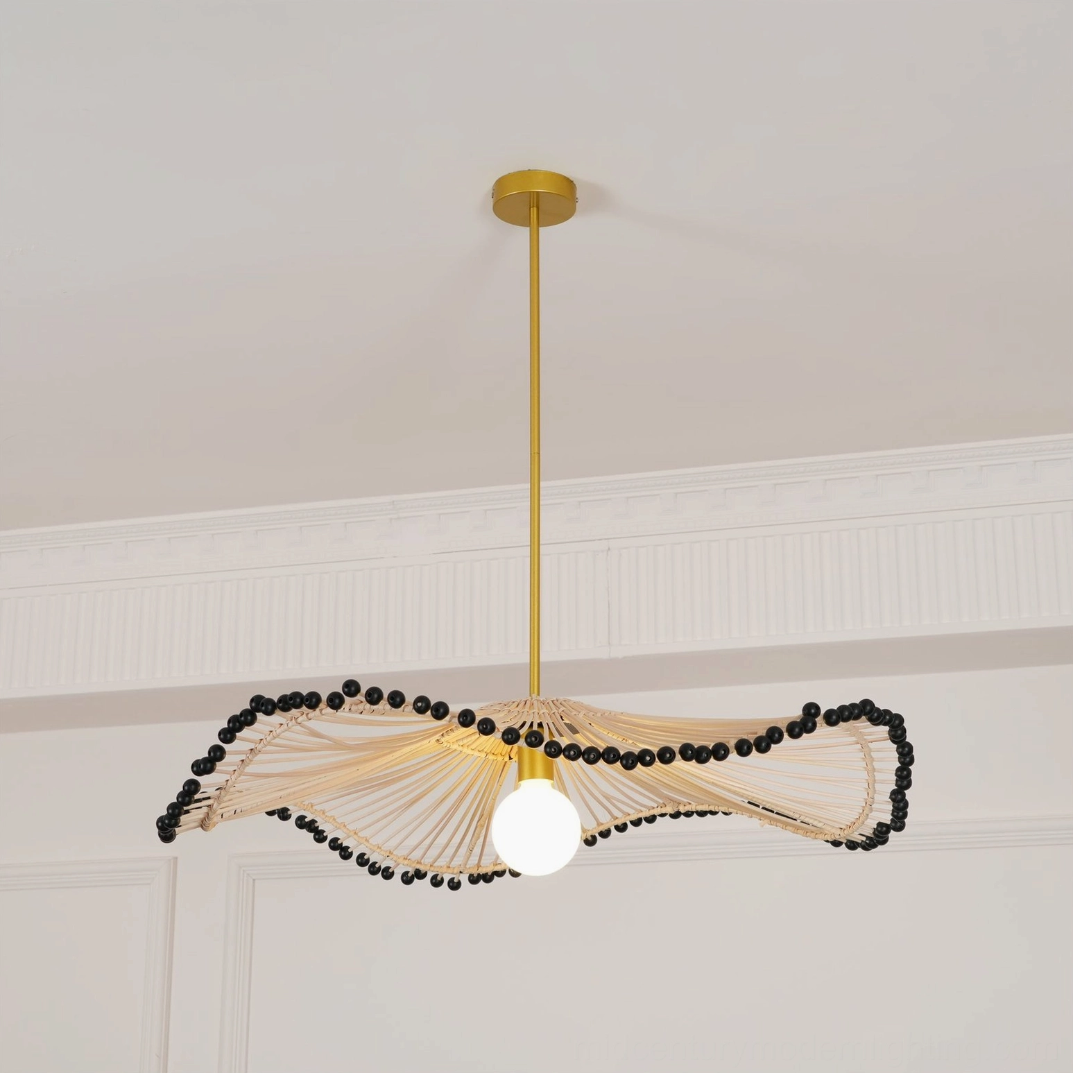 Long wavy rattan pendant chandelier installed in minimalist white room demonstrating bohemian lighting aesthetic