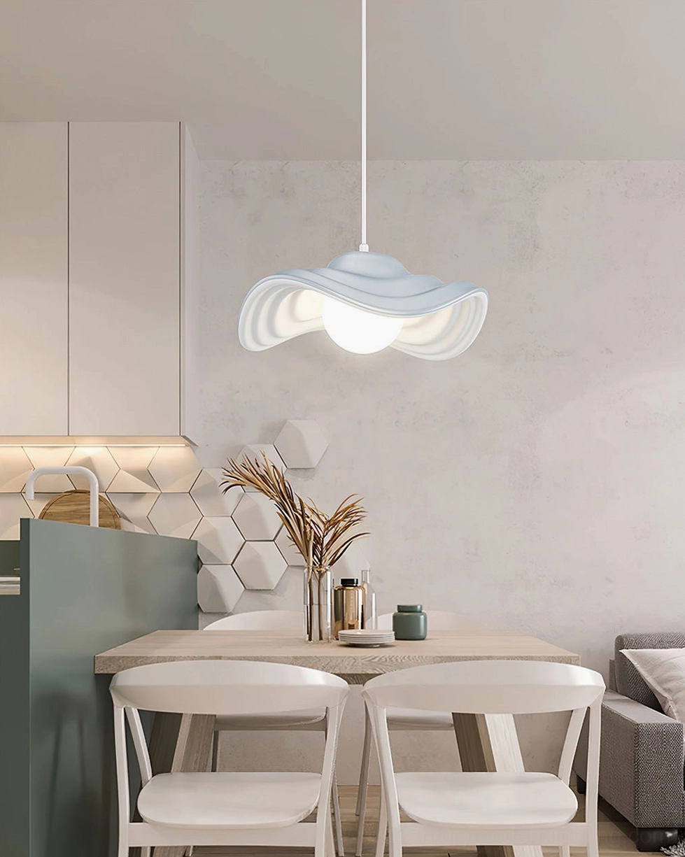 Light blue-grey wavy pendant lamp hanging over open kitchen island with contemporary minimalist home decor and natural lighting