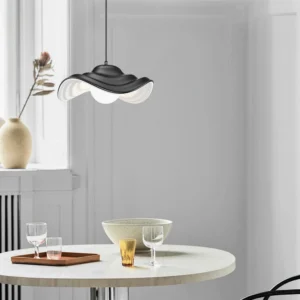 Black wavy pendant lamp installed above modern dining table in contemporary interior, creating sculptural focal point in neutral home decor
