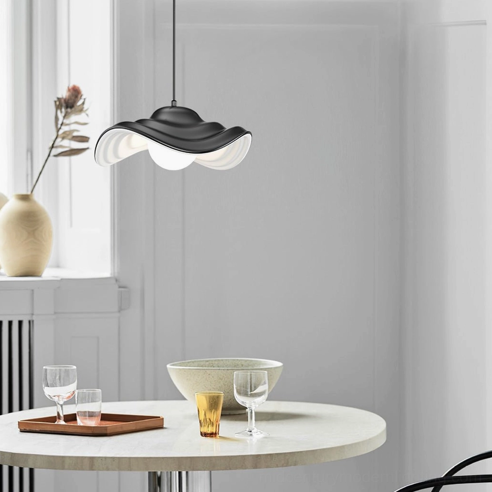 Black wavy pendant lamp installed above modern dining table in contemporary interior, creating sculptural focal point in neutral home decor