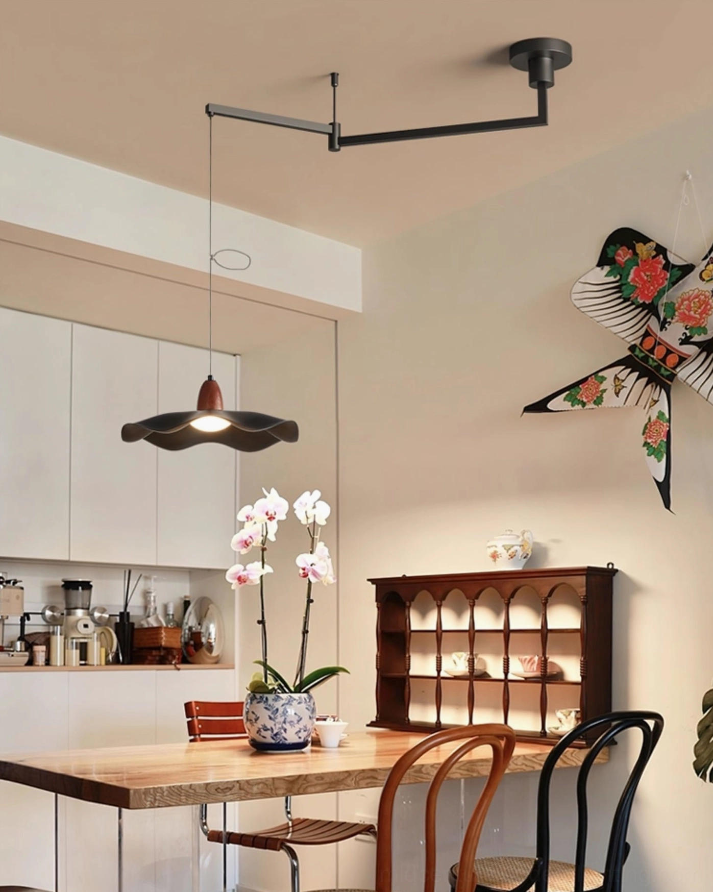 Sculptural pendant light in personalized warm minimalist dining space with floral and butterfly wall décor