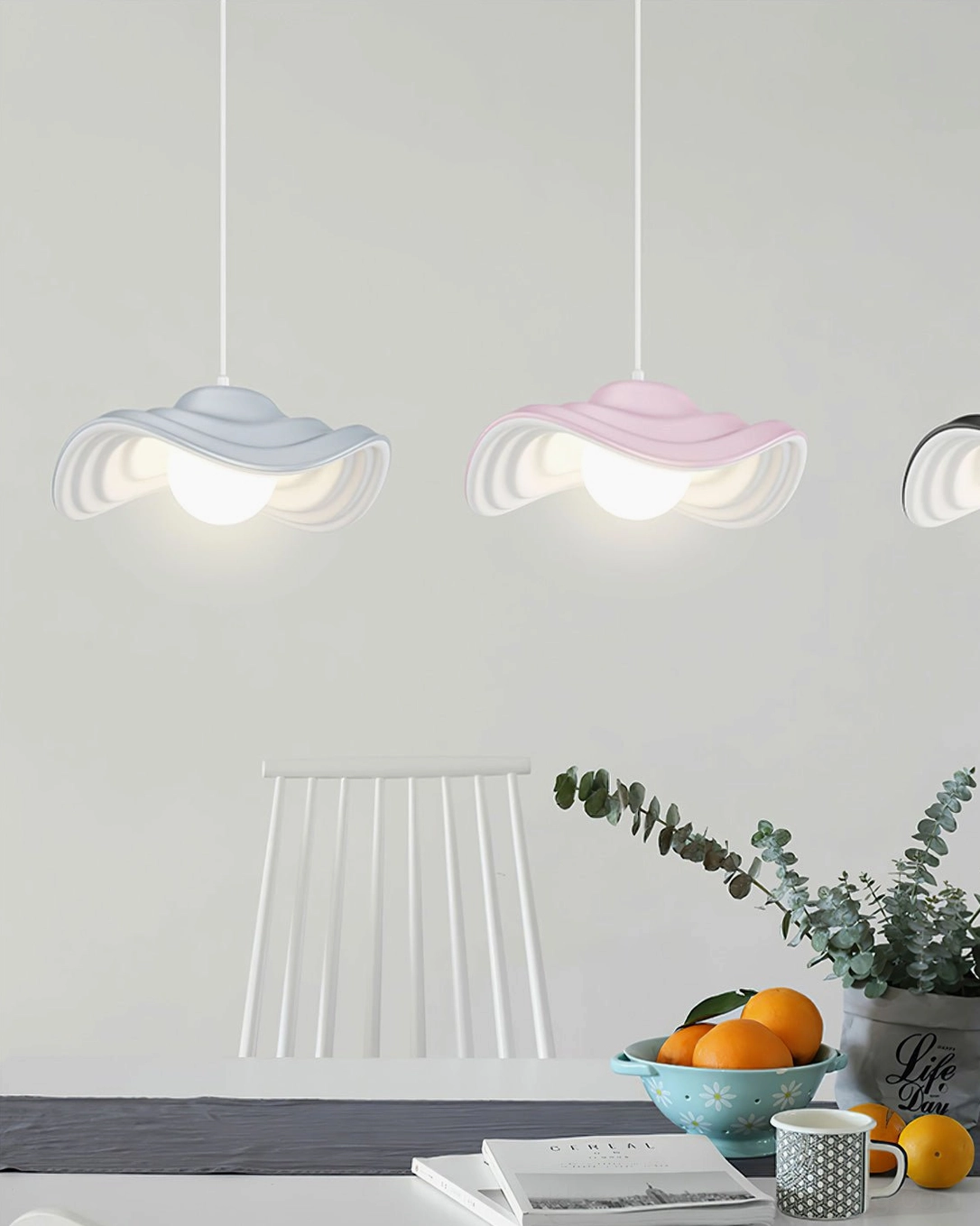 Close-up view of pastel wavy pendant lamps with soft rippled edges suspended above modern dining area, showing organic resin design details