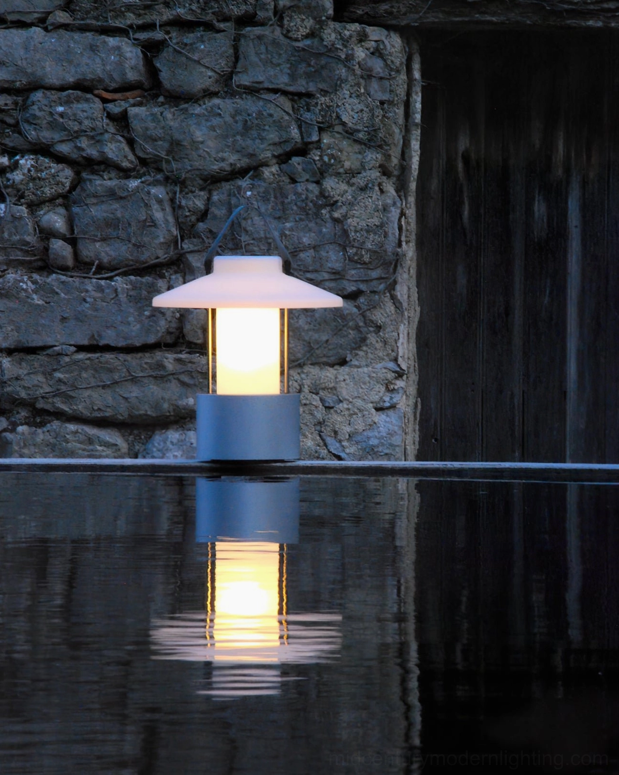Waterproof outdoor table lamp with grey base reflecting light on water surface at night