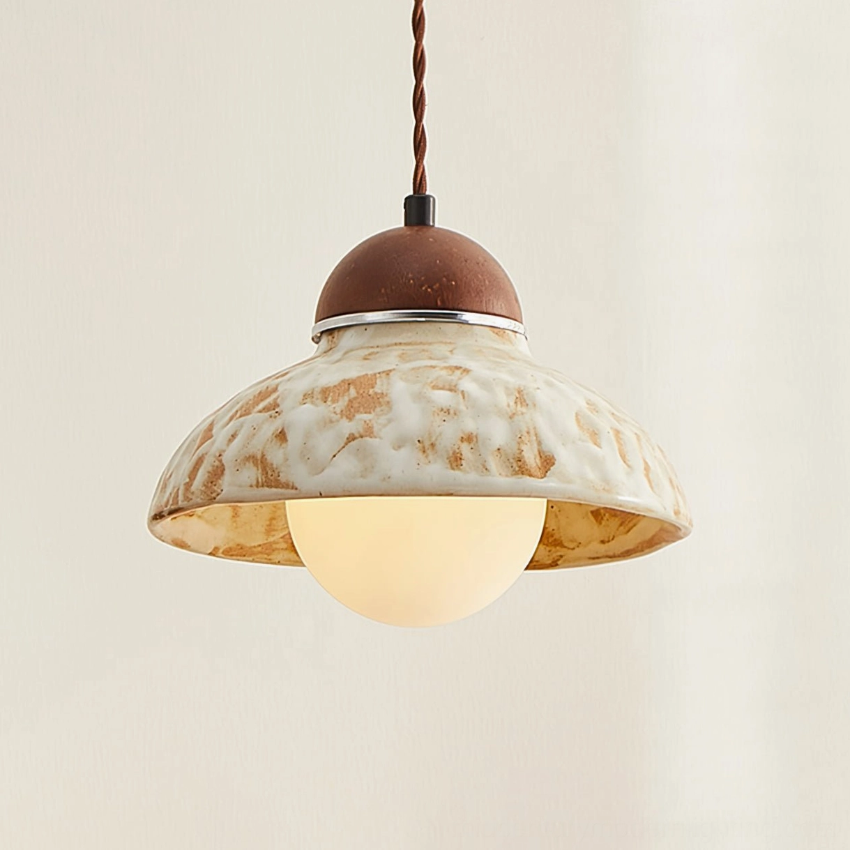 Wella pendant overhead view showing twisted brown fabric cord and lit bulb inside ceramic dome
