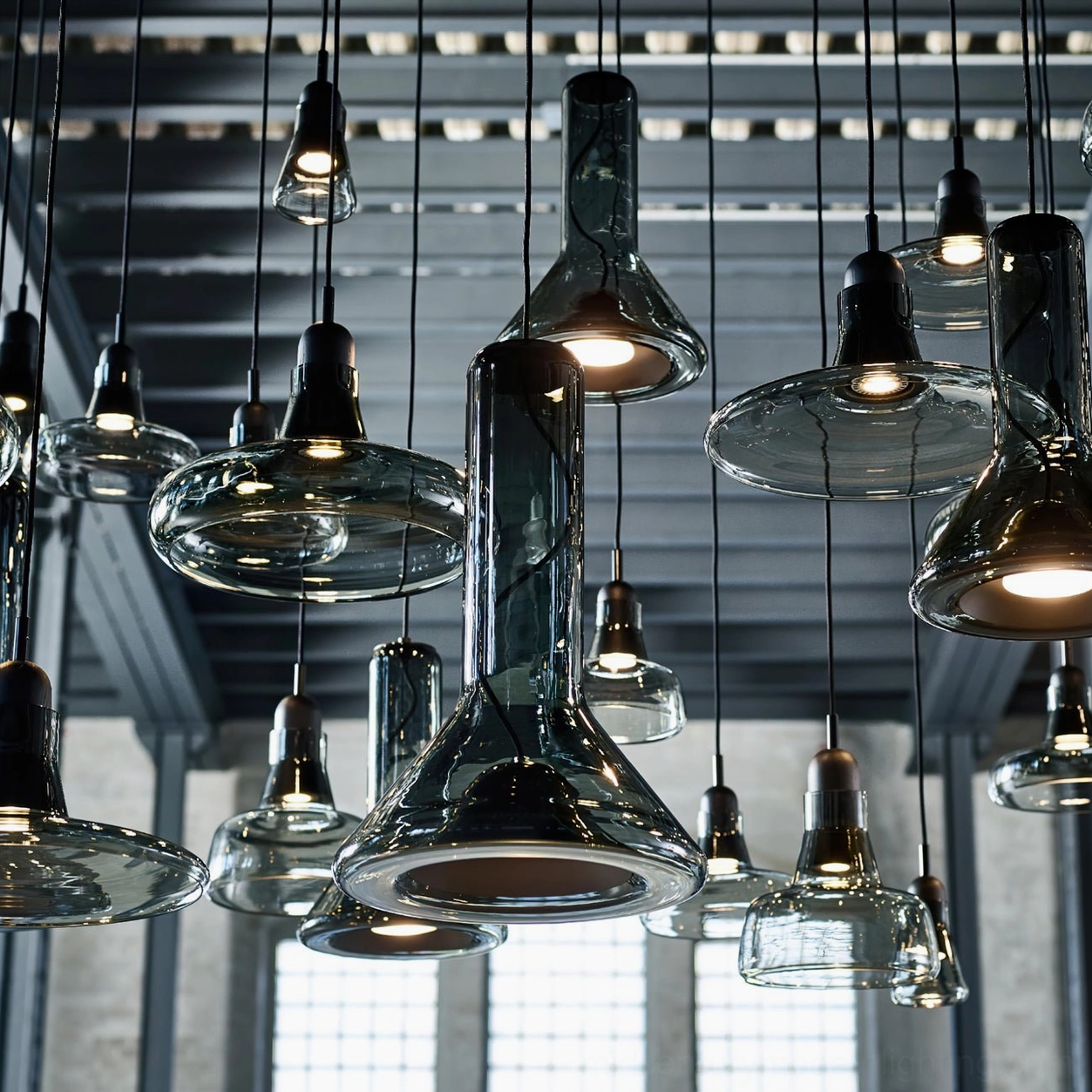 Cluster of mixed colour whistle pendant lamps in high-ceiling industrial interior space