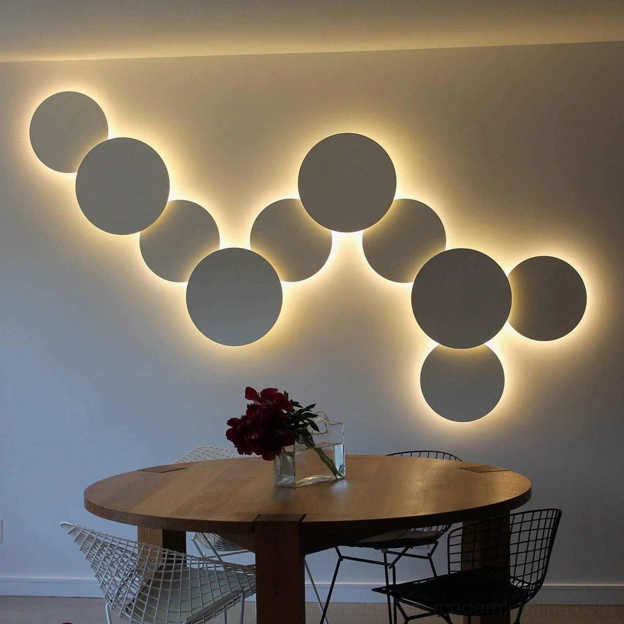 White and gray geometric disc wall sconce backlit in minimalist dining room with wooden furniture and warm ambiance