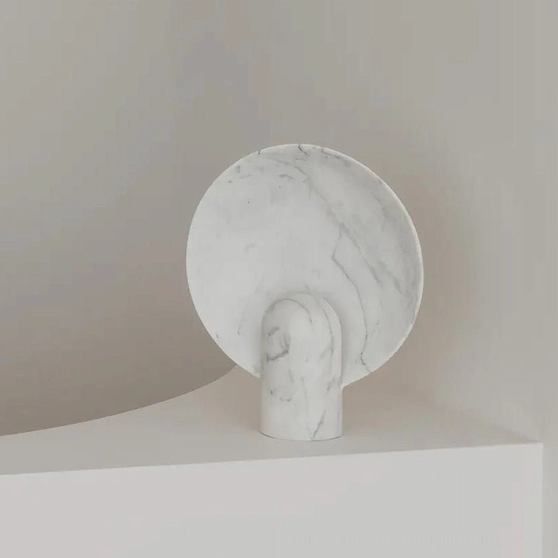 Solid white marble table lamp with subtle veining on studio display plinth illustrating sleek minimalist design and refined modern aesthetic