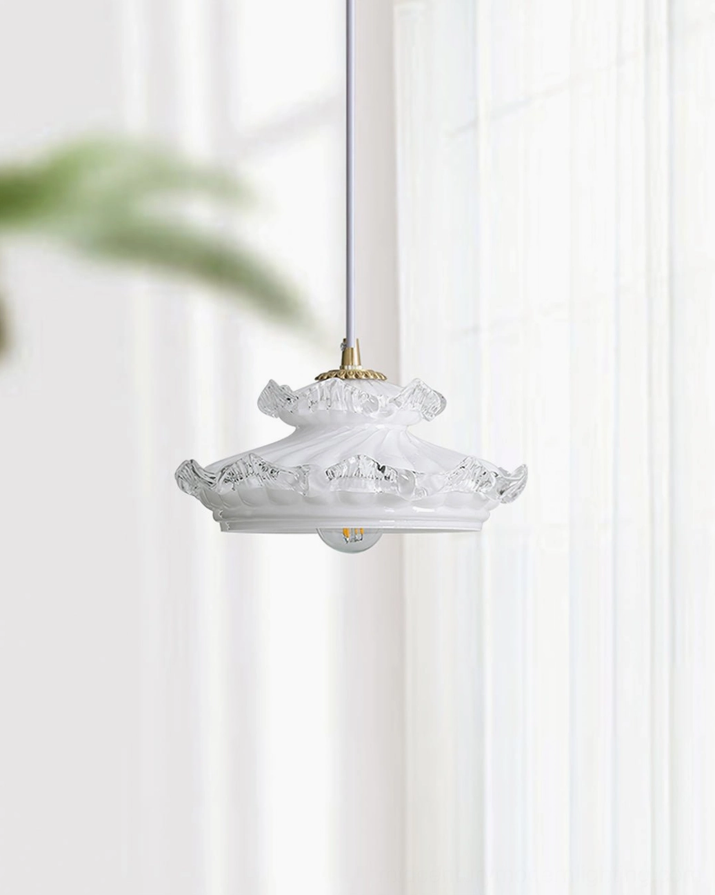 White vintage pendant lamp with ruffled glass trim beside bright window with sheer curtains