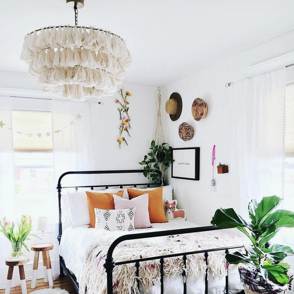 White fluffy tiered tassel chandelier in bright bohemian bedroom creating soft ambient lighting