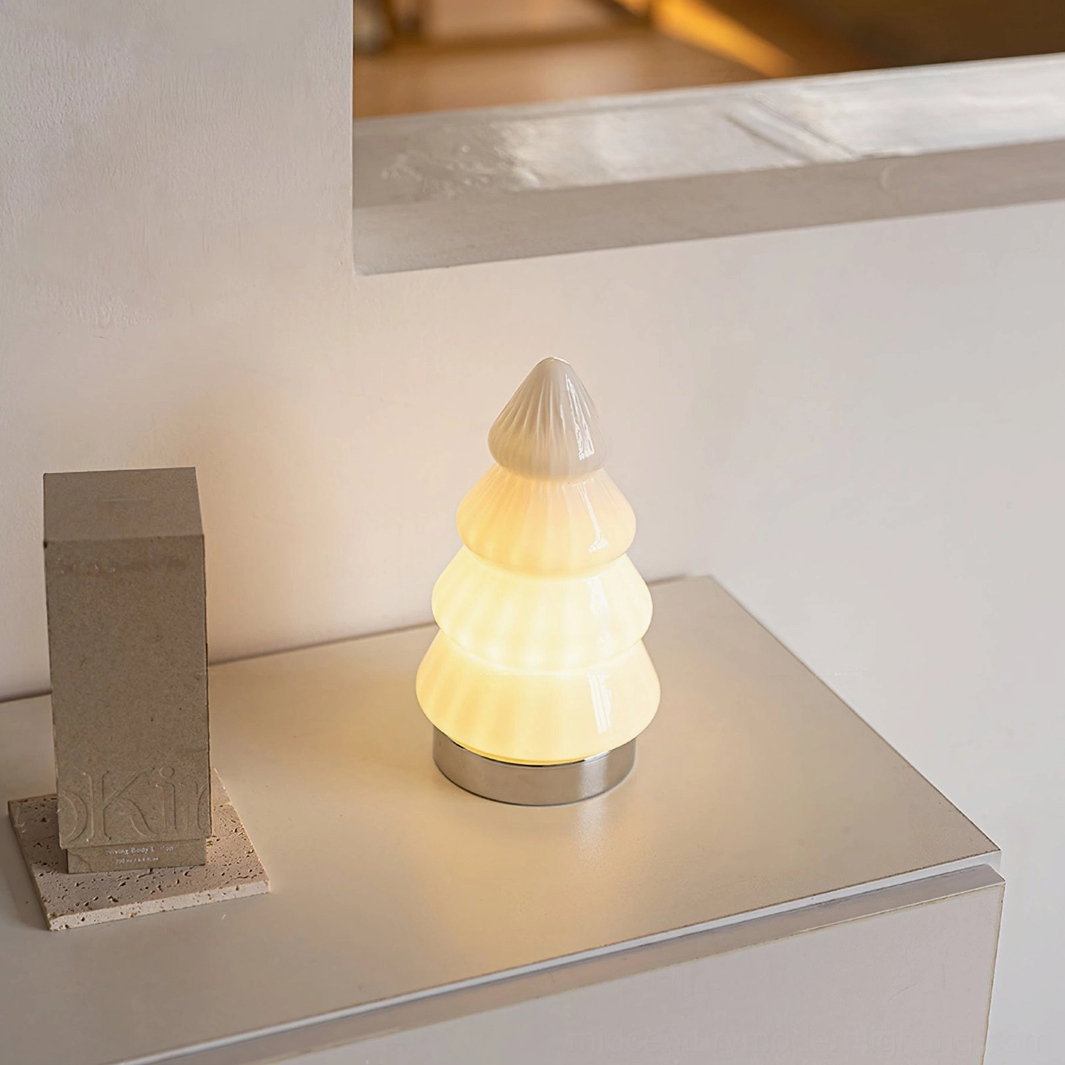 Glowing white tree lamp on light grey countertop with concrete decor creating warm ambient lighting in modern home
