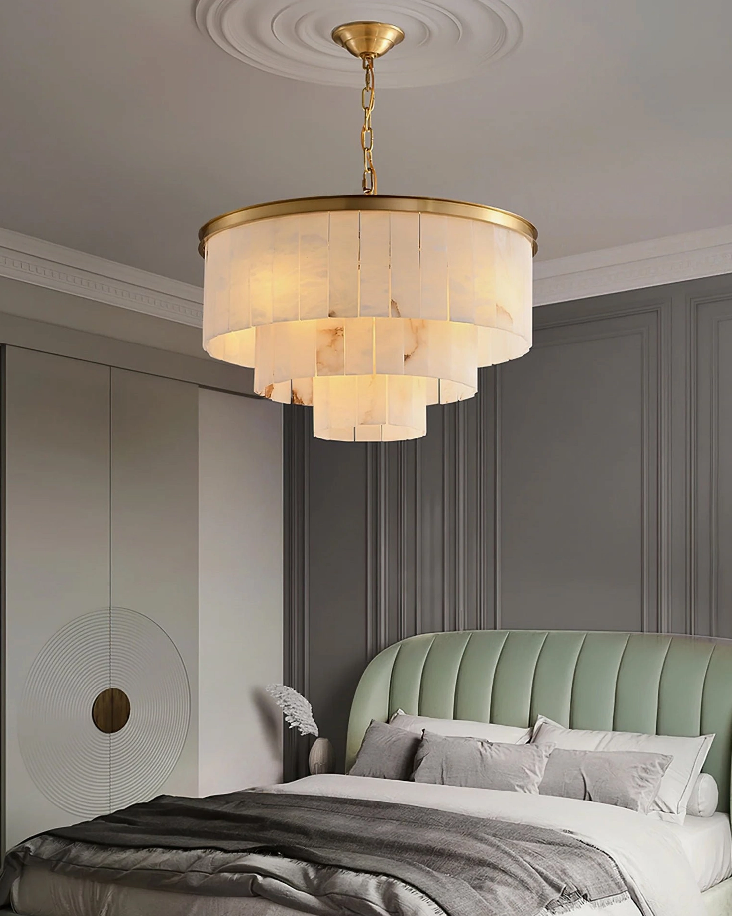 3-layer alabaster chandelier overhead installation in luxury master bedroom with green tufted headboard