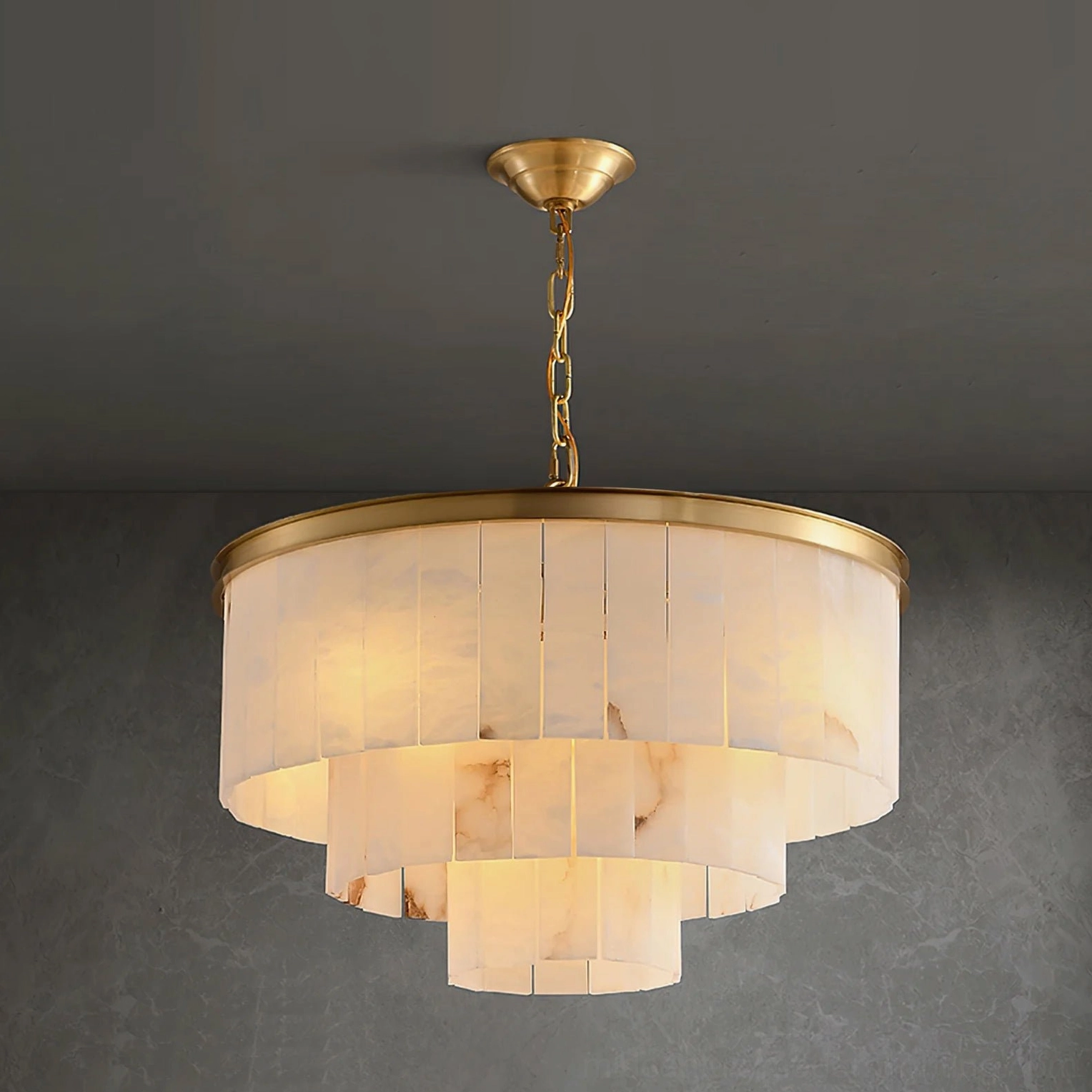 Low-angle frontal view of brass suspension chain and canopy with warm illuminated layered stone panels