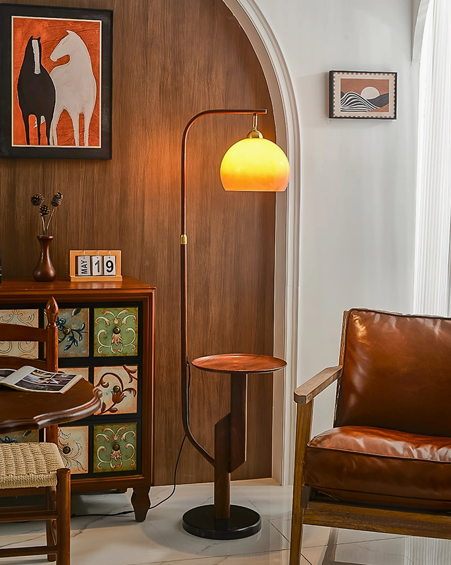 Winona arc floor lamp in mid-century modern living room with black base, warm amber light, and retro wall art