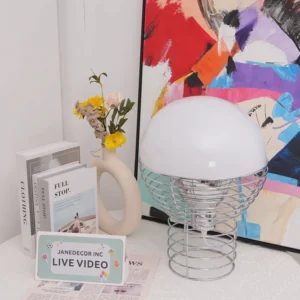 Modern wire cage table lamp styled on home decor table with three-quarter view showing geometric metal frame