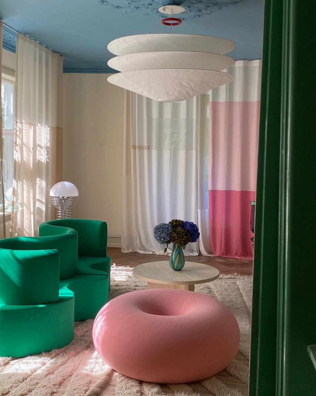Wire floor lamp with spherical shade in colorful modern interior with green seating and pink accent furniture