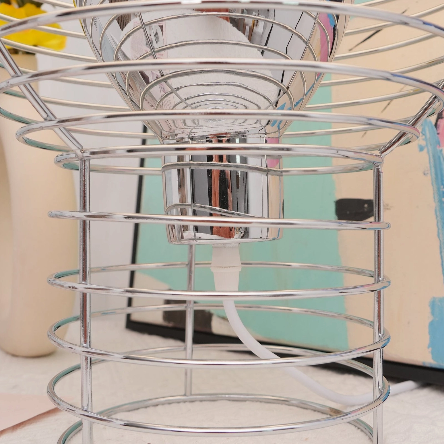 Bottom-up studio view of wire cage lamp showing exposed socket spiral metal design and power cord