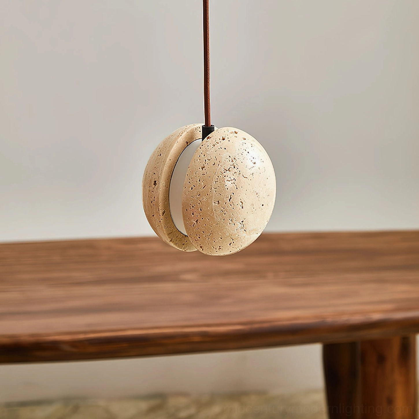Wisteria travertine pendant lamp above long wooden dining table, low angle front view, porous stone texture detail, warm illumination