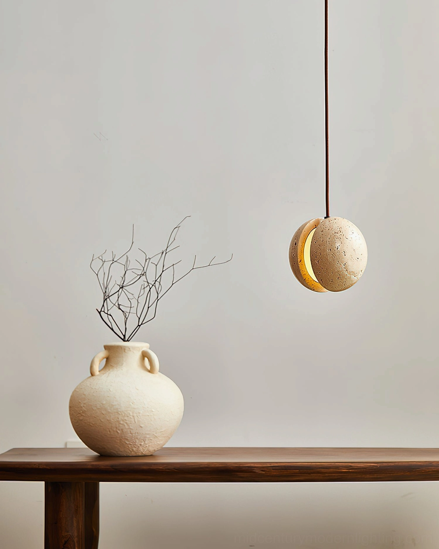 Wisteria travertine pendant lamp in entryway with console table, ceramic vase and dried botanicals, side angle view, beige stone finish
