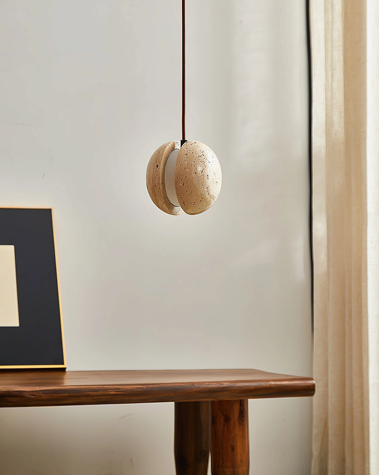 Wisteria pendant lamp above wooden table with mid-century decor and framed wall art, side view, sculptural stone lighting fixture