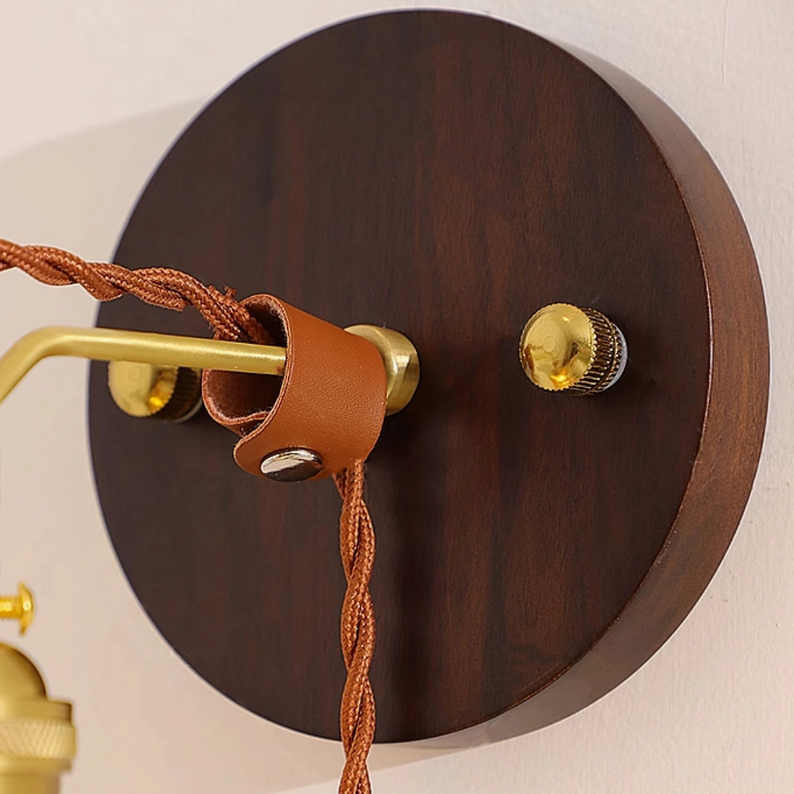 Detailed view of solid wood backplate with brass dimmer knob and leather cord fastener hardware