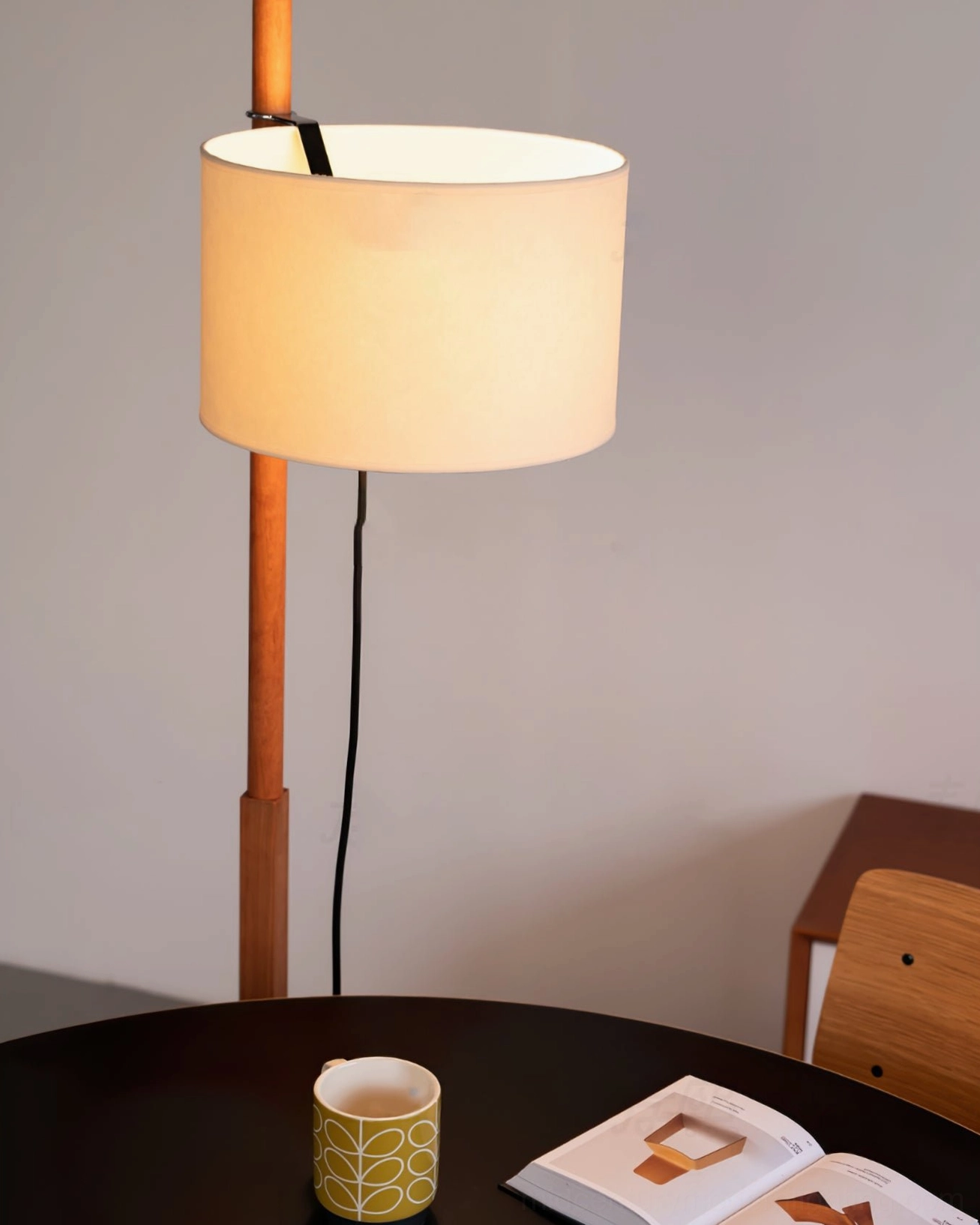 Wooden floor lamp showing pull cord switch and fabric shade from side angle