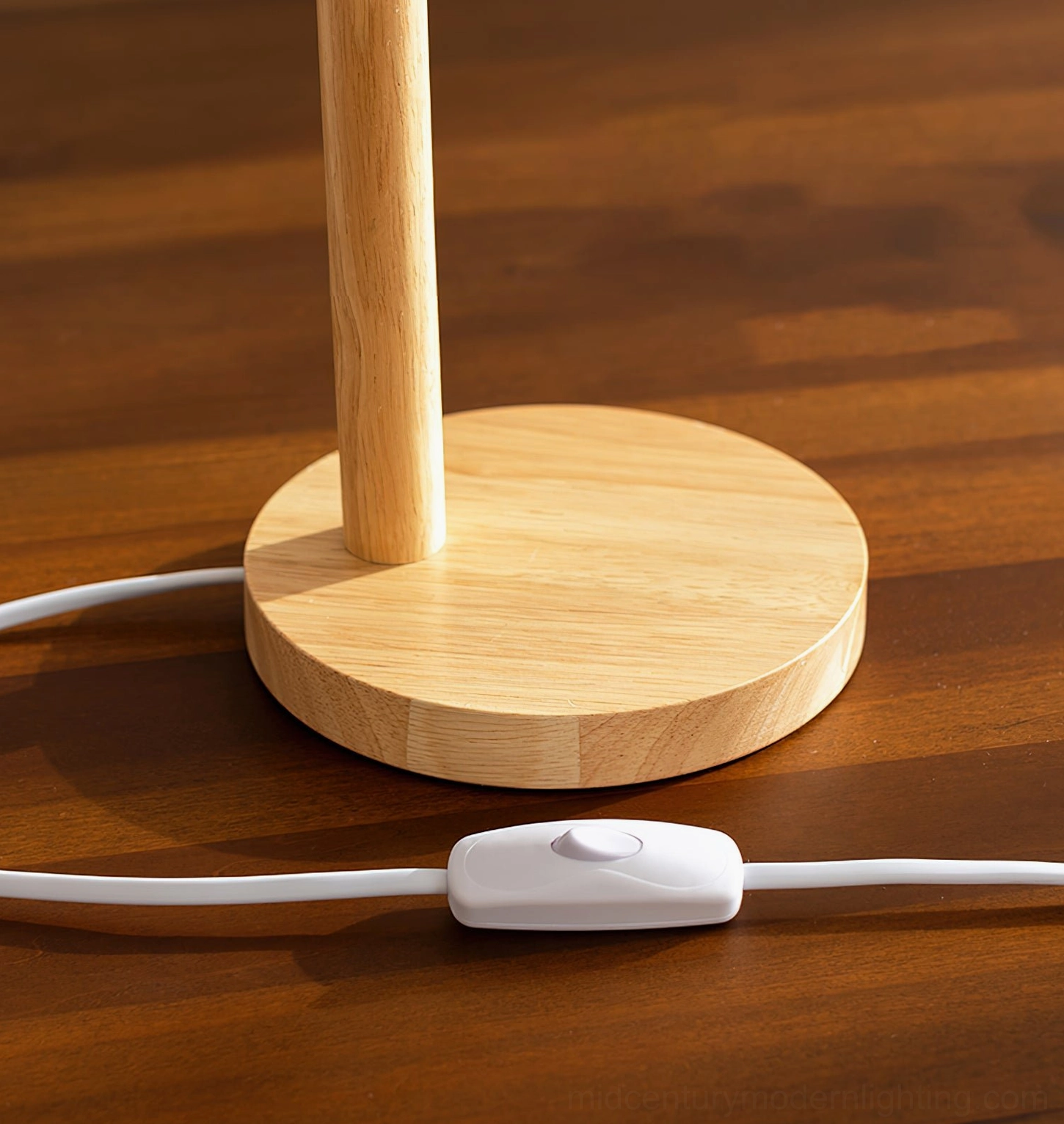 Wooden lamp base and power cord flat overhead view showing round solid wood base and inline white push-button switch