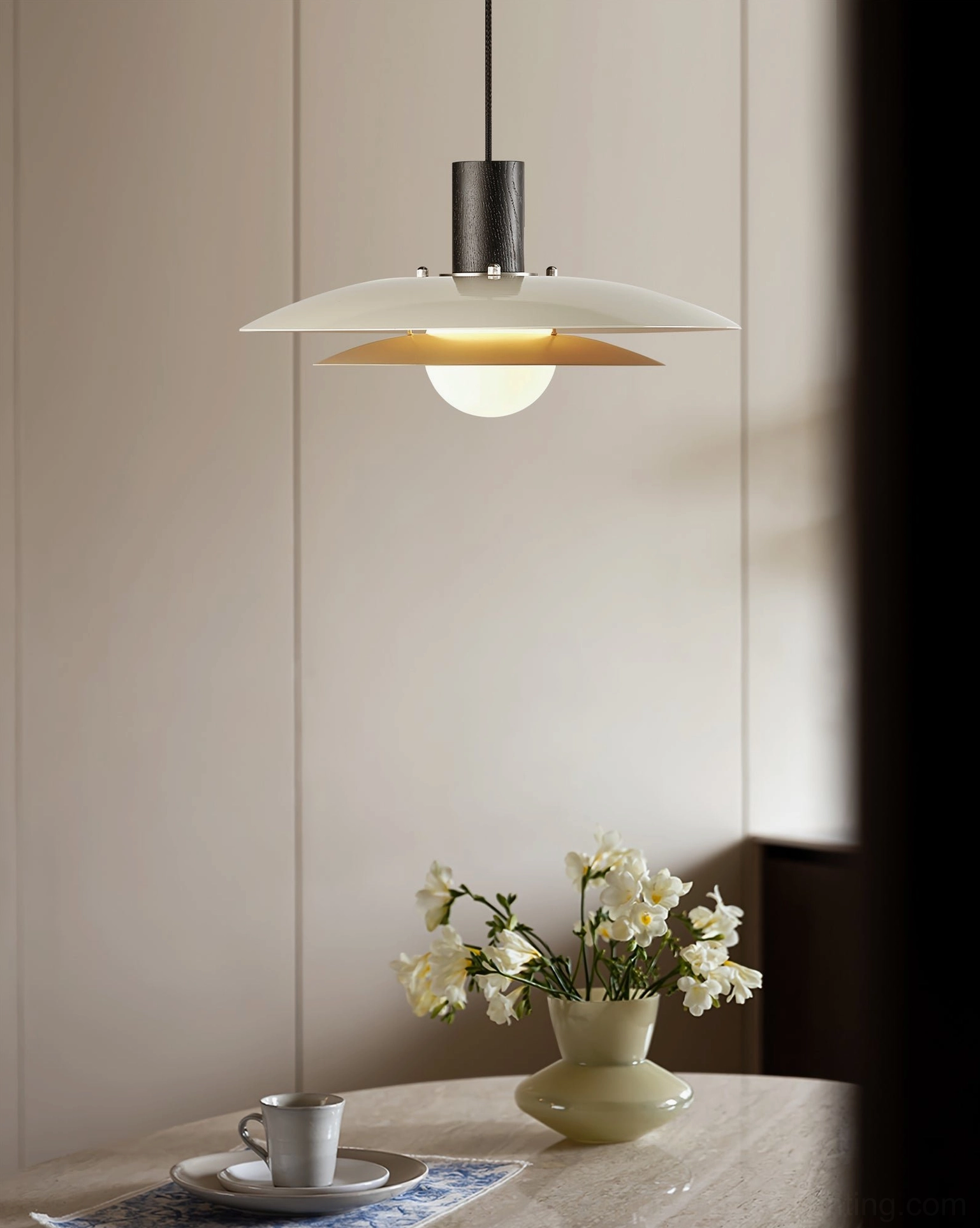 Wood saucer pendant lamp illuminating small dining nook with marble table and floral centerpiece