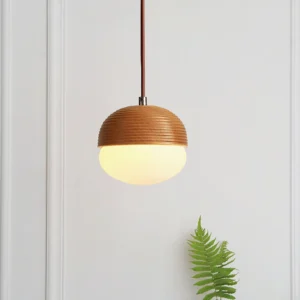 Wood grain pendant light illuminated warm, showing frosted glass diffuser and chrome metal components in bedroom setting