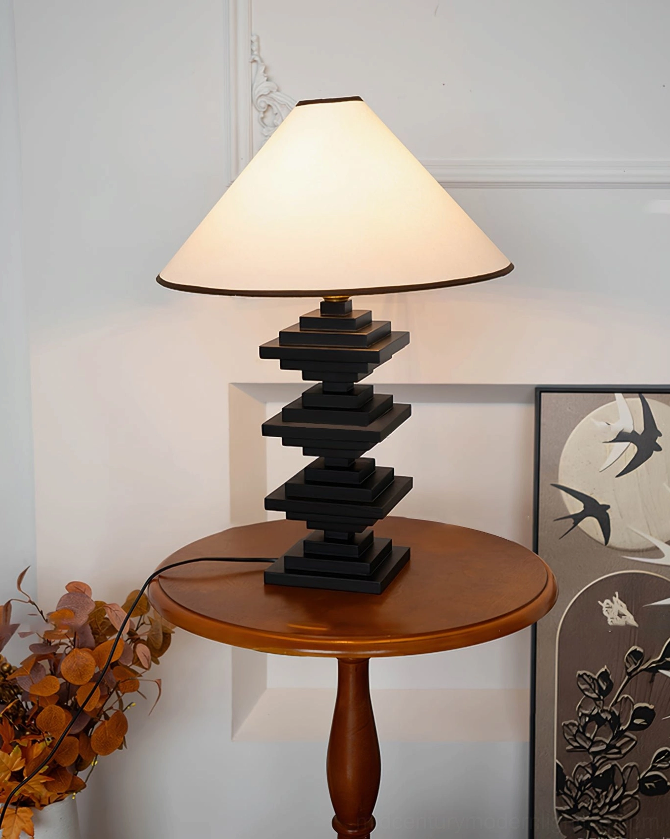 Minimalist stacked wooden tower lamp on round side table with white wall and decorative art panels