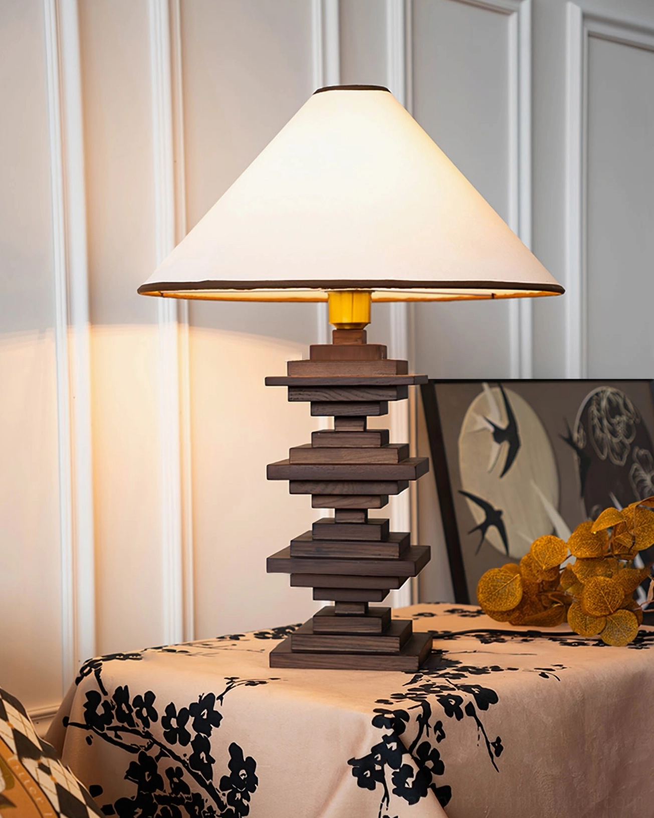 Contemporary stacked wood tower lamp three-quarter view on side table with striped wall and art prints