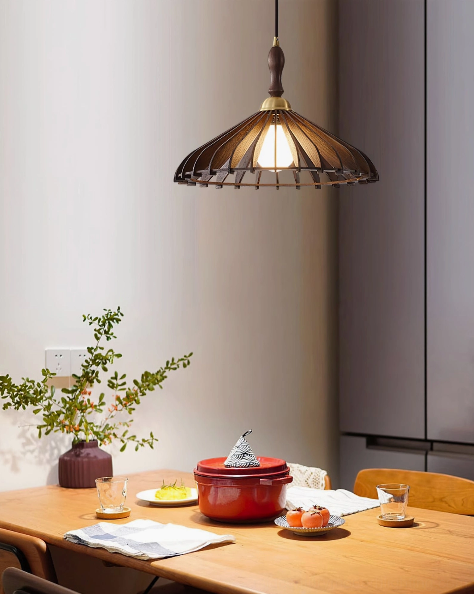 Natural wood umbrella pendant lamp in kitchen dining area with brass details and tableware styling
