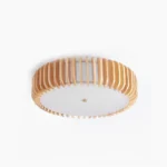 Wooden drum flush mount ceiling light with vertical natural wood slats and frosted white acrylic diffuser panel in studio lighting