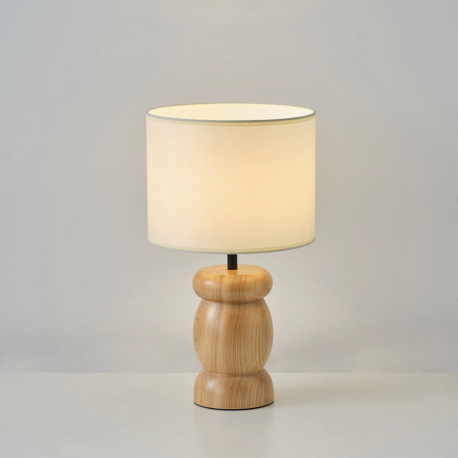 Unlit wooden table lamp with curved wood base, beige cylinder fabric shade, clean grain detail, front studio view